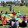 A picture of kids at the park with a large kite at the Unlocked Potential back to school fun bash camp in Flagstaff, AZ